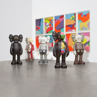 A collection of assorted 4 foot KAWS Companion figures exhibit in a gallery space, as collectors wonder, ‘Are KAWS figures a good investment?”.