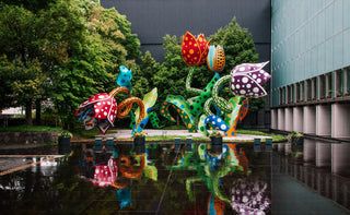An outdoor Kusama art exhibit at Matsumoto City Museum of Art in Nagano, where giant polka-dot flower sculptures rise beside a reflecting pool.
