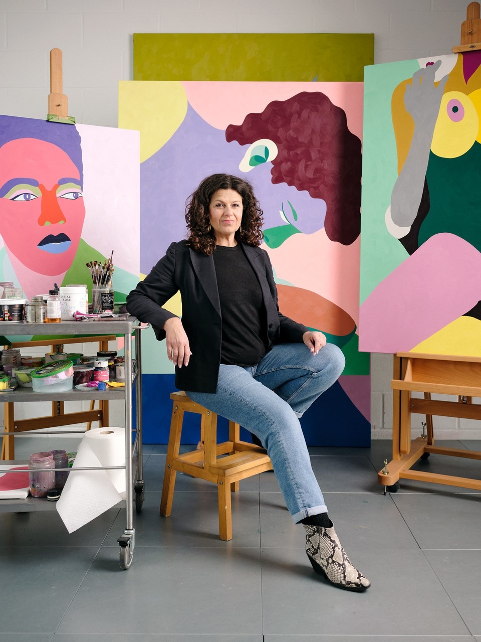 Helen Beard seated in studio with her works, contemplating the advantage of being a woman artist in this era, as the female art market blossoms.