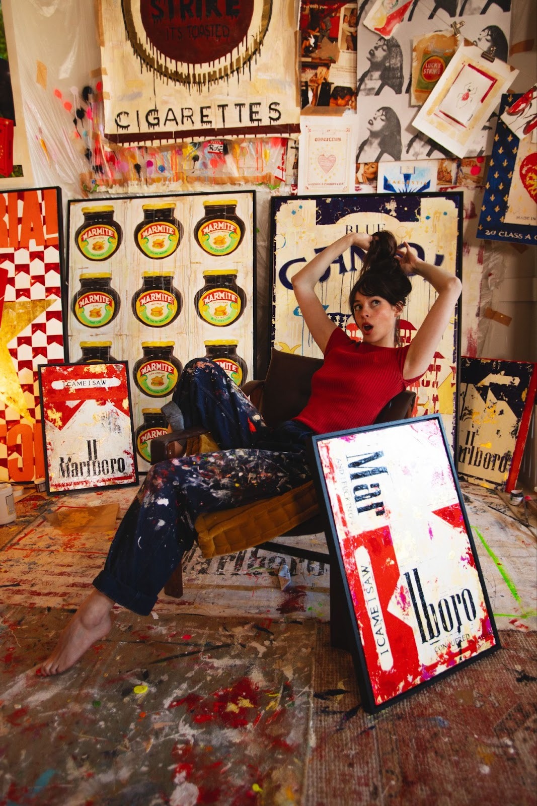 Charlotte Rose sits in her studio, surrounded by her works. She is one of the promising young women artists featured in the Maddox Gallery women and art exhibition, HER.