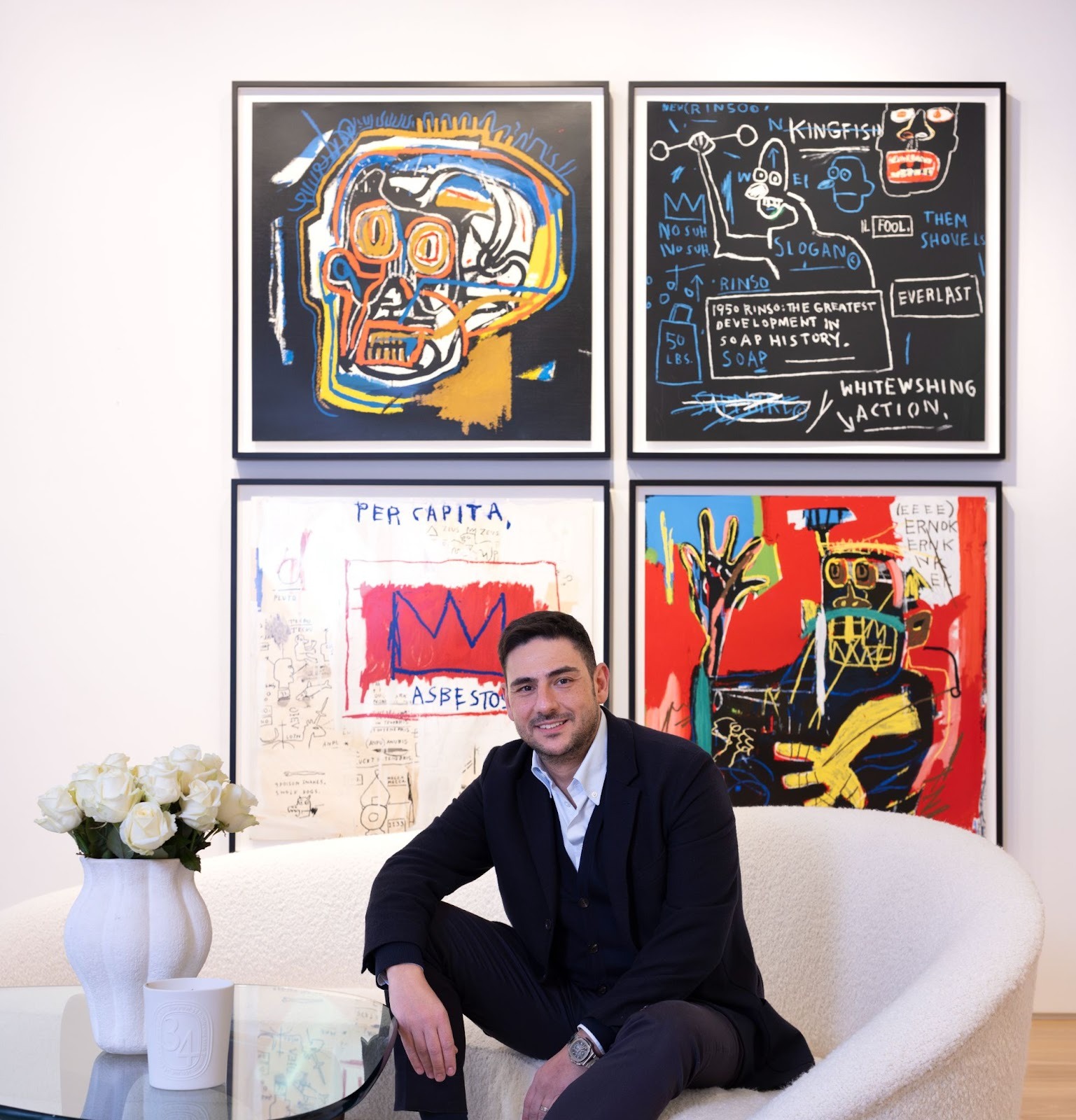 A Maddox Gallery art advisor sits ready to consult about the best way to invest in art in front of four works by Jean-Michel Basquiat; Head; Rinso; Per Capita; and Ernok.