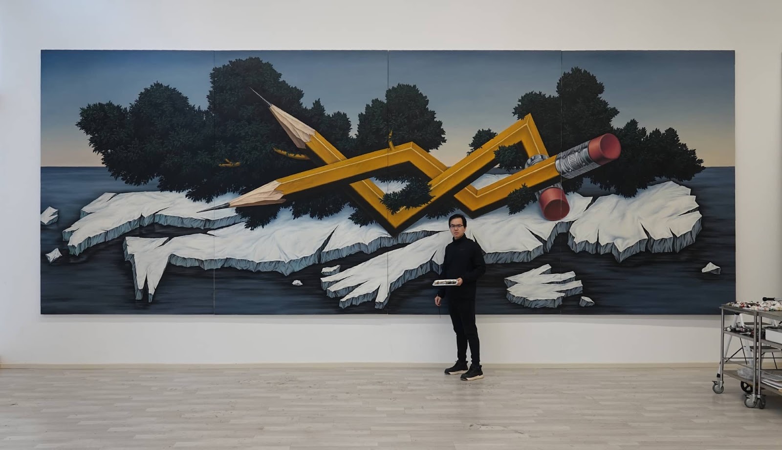 Chinese Contemporary painter Zhou Song, poses with his painting of a human-shaped island at his solo exhibition.