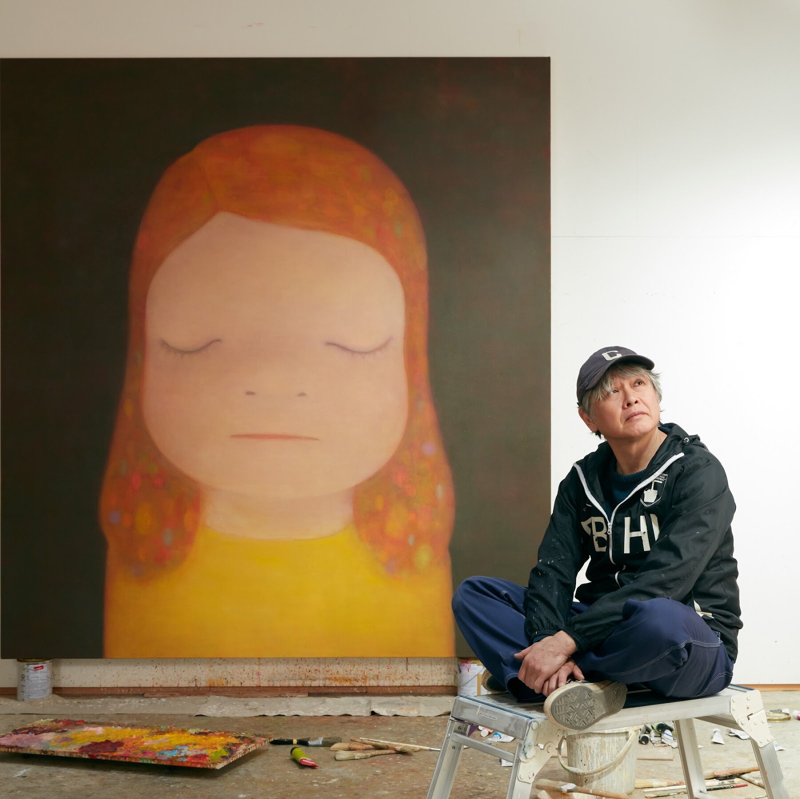 Artist Yoshitomo Nara poses in his home studio in Tochigi Prefecture, Japan, alongside one of his famous Japanese Contemporary paintings of an emotive child.