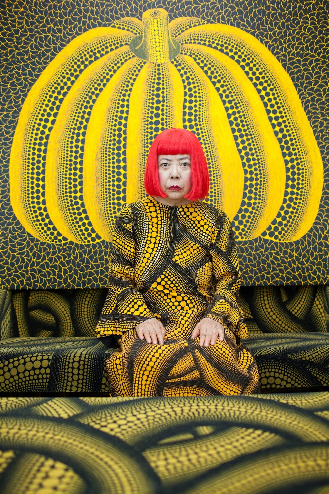 Japanese Contemporary Artist Yayoi Kusama wears a costume with her signature polka dot motifs as she poses for a portrait, appearing to blend into her &lsquo;Pumpkin&rsquo; painting, behind.